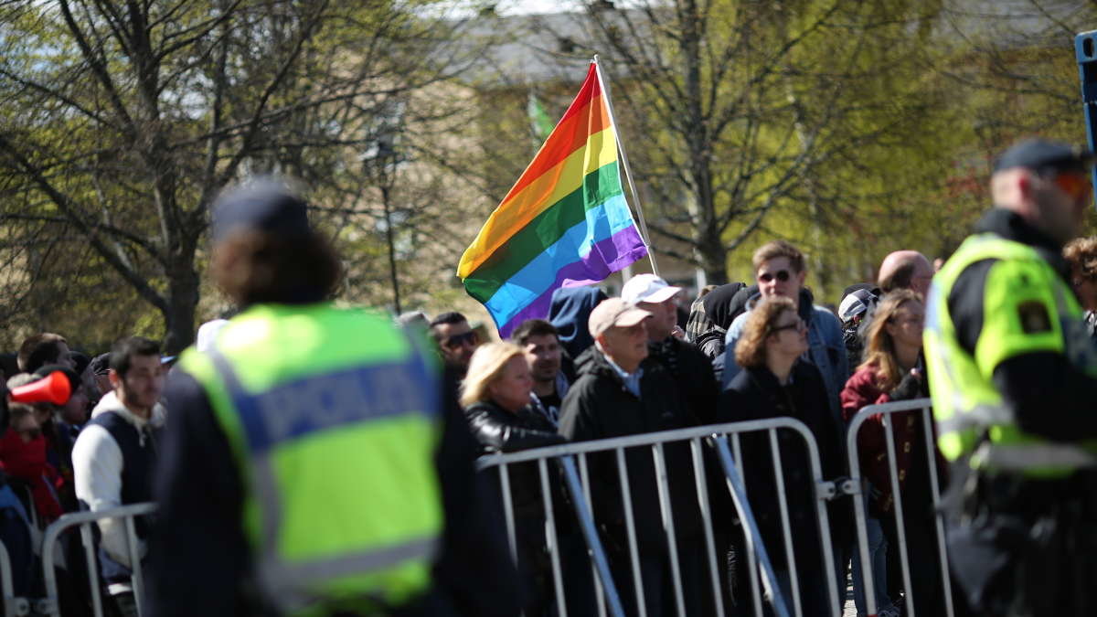 En pride-flagga syns bland motdemonstranterna. 